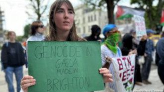 Woman holding sign saying 'Genocide in Gaza made in Brighton'