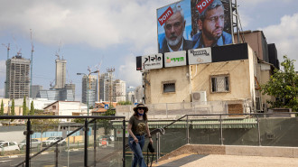 A woman walks near a billboard displaying portraits of Hamas leader Mohammed Deif (R) and Ismail Haniyeh with the slogan "assassinated" reading in Hebrew, in Tel Aviv, on August 2, 2024. 