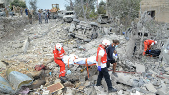 Paramedics with the Lebanese Red Cross transport a body unearthed from the rubble at the site of an Israeli airstrike that targeted the northern Lebanese village of Aito on October 14, 2024. (Photo by FATHI AL-MASRI/AFP via Getty Images)