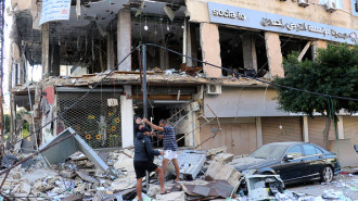 People inspect the damage at the site of an overnight Israeli airstrike that targeted a branch of the Al-Qard Al-Hassan finance group in the southern city of Tyre on October 21, 2024. (Photo by BILAL KASHMAR/AFP via Getty Images)