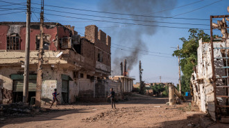 Boys check a fire that broke out in a destroyed house in a war-torn neighborhood in Omdurman