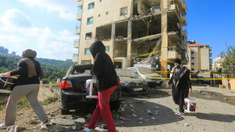 Residents walk past damaged cars in front of an apartment destroyed in an Israeli strike in the Dawhet Aramoun area, south of Beirut, on November 13, 2024.