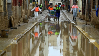 Agents wearing protective jumpsuits take part in cleaning works in a street covered in mud in Paiporta, south of Valencia, eastern Spain, on 13 November 2024.