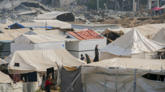 People walk among rows of makeshift tents in Al-Bureij refugee camp, central Gaza Strip