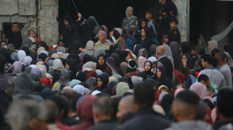 Palestinians wait in a queue to receive bread outside a bakery in Khan Younis