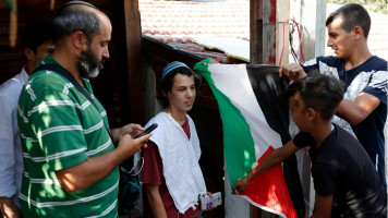 Palestinian youth raise flag Israeli settlers Sheikh Jarrah [GETTY]