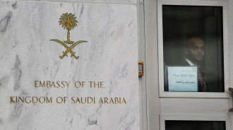 An embassy staffer peers through a glass 