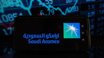 In this photo illustration a Saudi Aramco logo seen...