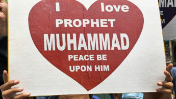 A man holding a sign reading: "I love Prophet Muhammad, peace be upon him."