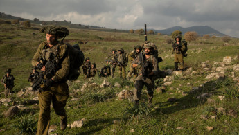 Soldiers walk on stony terrain