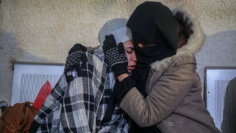 Two Palestinian women embrace. One appears visibly upset