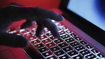 A hand hovering over and about to type on a laptop keyboard.