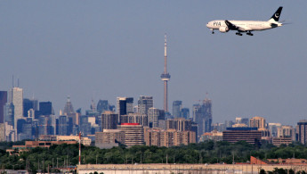 A Pakistan International Airlines flight is arriving at Toronto Pearson International Airport as seen from Danville Park in Mississauga, Ontario