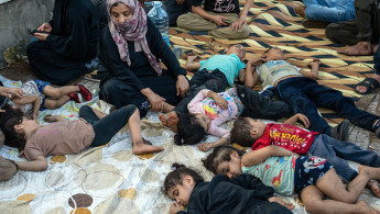 A woman watches over sleeping children as shelter outside after being displaced by Israeli airstrikes on September 28, 2024 in Beirut, Lebanon. 