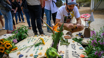  Daniel Lifschitz (R), grandson of hostage Oded Lifschitz, lights a memorial candle at the grave for his best friend Dolev Yehud who was thought to be a hostage but was later killed on the 7th and his body was taken to Gaza, on the first anniversary since Hamas attacked one year ago on October 07, 2024 in Nir Oz, Israel.