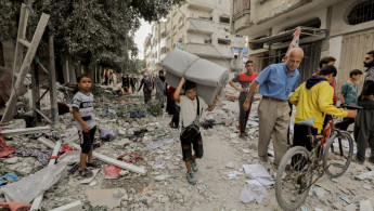 A boy carries belongings through the rubble of the Abdel Hadi family home in Bureij camp