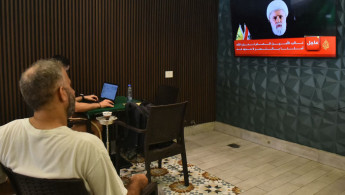 People follow at a cafe in Beirut a televised speech by Hezbollah deputy chief, Naim Qassem