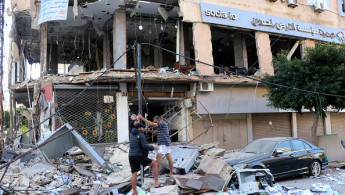 People inspect the damage at the site of an overnight Israeli airstrike that targeted a branch of the Al-Qard Al-Hassan finance group in the southern city of Tyre on October 21, 2024. (Photo by BILAL KASHMAR/AFP via Getty Images)