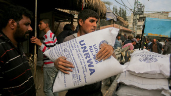 A man clutches a large sack of flour labeled UNRWA during distribution efforts in Deir al-Balah, Gaza, on November 2, 2024. The Turkish Disaster and Emergency Management Presidency (AFAD) has provided flour amidst a food crisis caused by ongoing Israeli attacks. 