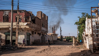 Boys check a fire that broke out in a destroyed house in a war-torn neighborhood in Omdurman