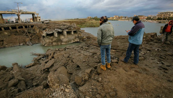 People inspect the destroyed bridge on the Lebanese side of the Al-Arida border crossing with Syria on November 27, 2024. (Photo by IBRAHIM CHALHOUB/AFP via Getty Images)