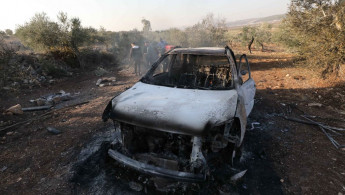 People inspect a completely burned and destroyed vehicle following an Israeli drone strike in the northern West Bank city of Tubas on 3 December 2024. Two Palestinians were killed in the Israeli attack. [Getty]