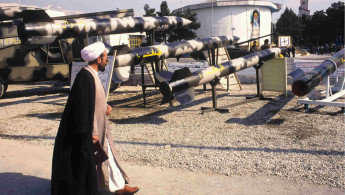 Iran clergyman walks past missile display