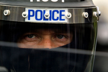 A Royal Ulster Constabulary (RUC) riot police officer looks out from behind his face shield 30 June, 2001 in Belfast, Northern Ireland.