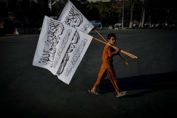 A boy carries Taliban flags to sell in the Karte Mamorin area of Kabul on August 22, 2021. (Photo by Hoshang Hashimi / AFP)