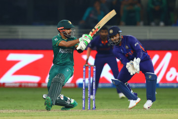 Babar Azam of Pakistan plays a shot as Rishabh Pant of India looks on during the ICC Men's T20 World Cup match between India and Pakistan at Dubai International Stadium on October 24, 2021 in Dubai, United Arab Emirates. (Photo by Francois Nel/Getty Images)