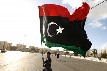 A Libyan man waves his national flag as protesters gather for a demonstration calling on the international community to lift the ban on arming or munitioning the Libyan army, in the eastern coastal city of Benghazi on February 27, 2015