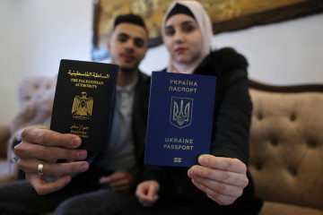 Ukrainian Viktoria Saidam (R), accompanied by her Palestinian husband Ibrahim Saidam, show their passports at their family home in the refugee camp of Bureij in the central Gaza Strip on March 22, 2022