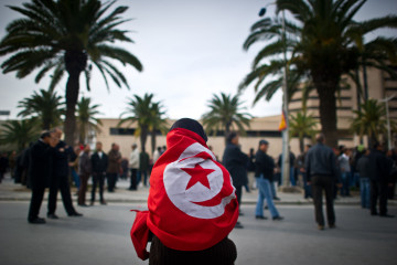 A woman, wearing a flag of Tunisia, demonstrates against Ben Ali's Constitutional Democratic Rally (RCD) in a new wave of anger about the presence of RCD stalwarts in the transitional government, on January 20, 2011, in Tunis. 