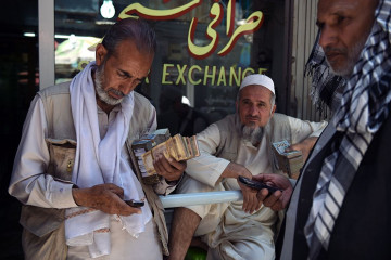 Afghan money changers calculate at the currency exchange Sarayee Shahzada market in Kabul 