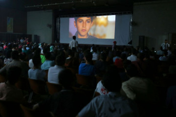 Palestinian families attend the screening of a movie during the opening of the "Red Carpet" cinema festival in Gaza City, on May 12, 2016