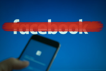 An iphone with a facebook login screen is seen with a striked out facebook logo