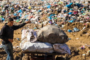 A Palestinian youth seen preparing himself to ride his cart at a large landfill in the town of Beit Lahia in the northern Gaza Strip