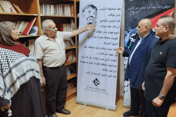 People standing next to a poster commemorating Yasser Arafat