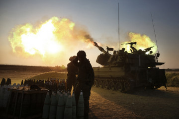 Israeli soldiers fir artillery cannons on the Gaza border