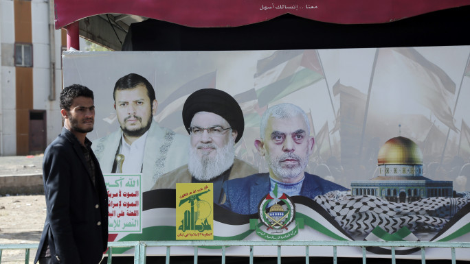 A Yemeni man walks next to a billboard with images depicting the Houthi leader Abdul-Malik Badreddin al-Houthi, Lebanon Hezbollah leader Hasan Nasrallah, and Yahya Sinwar, the Hamas military leader in the Gaza Strip, displayed in an exhibition launched in solidarity with Palestinians and against the Israeli sustained bombardment in Gaza on January 31, 2024, in Sana'a, Yemen. (Photo by Mohammed Hamoud/Getty Images)