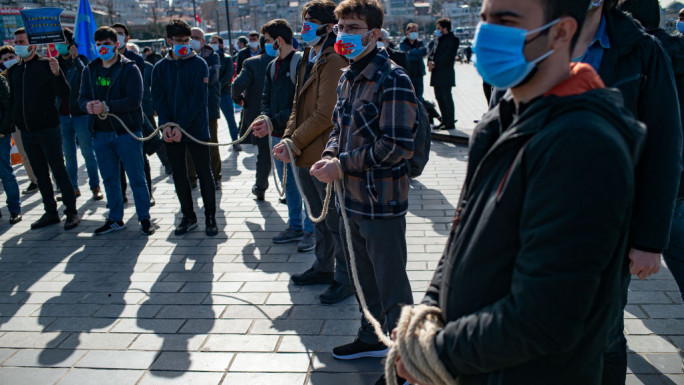 Members of the Muslim Uighur minority keep symbolically their hands tied with a rope as they demonstrate to ask for news of their relatives [Getty Images]