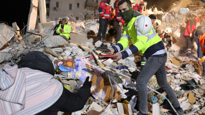 An emergency responder hands personal affects to a woman in hopes that she can identify whether or not the responders are close to recovering a survivor. [William Christou - TNA]