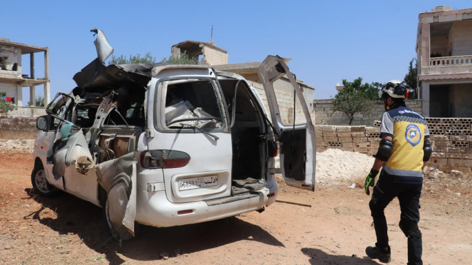 A man inspects a badly damaged van 