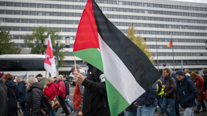 A demonstrator carries a Palestinian flag as he and others take part in a large-scale peace march on German Unity Day on October 3, 2024 in Berlin,