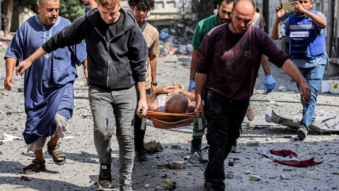 People carry on a gurney a man extricated from the rubble of a collapsed building following Israeli bombardment after his rescue in the Saftawi district in Jabalia in the northern Gaza Strip on October 15, 2024 