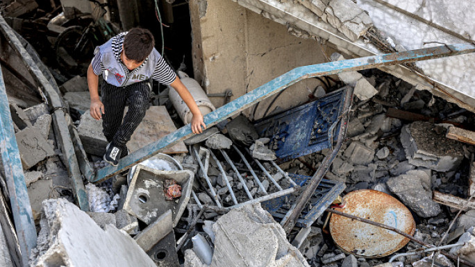 A boy climbs through the rubble of a collapsed building following Israeli bombardment in the Saftawi district in Jabalia in the northern Gaza Strip on October 15, 2024