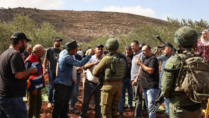 Israeli troops order Palestinian farmers and volunteers helping them to leave the field during the olive harvest season in the village of Qusra