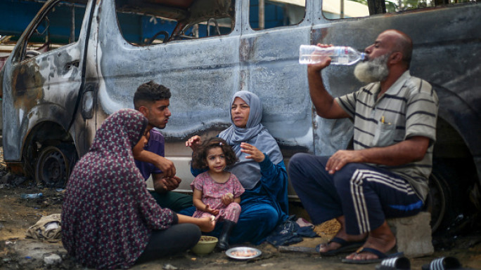 Palestinians have a meal at the site of an Israeli airstrike which hit tents for displaced people two days earlier in the courtyard of Al-Aqsa Martyrs Hospital in Deir al-Balah in the central Gaza Strip on October 16, 2024.