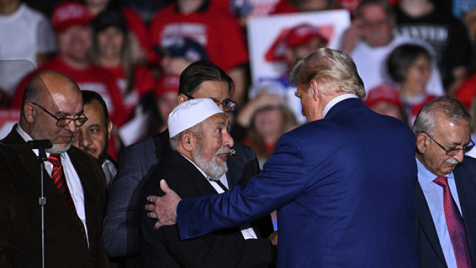 Republican candidate Donald Trump greets local leaders of the Muslim community who endorsedd him onstage during a campaign rally at the Suburban Collection Showplace in Novi, Michigan, October 26, 2024.