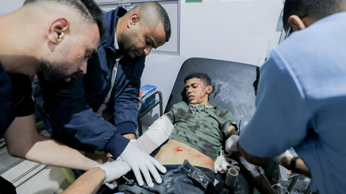 Doctors examine a young patient in a hospital bed at Al-Awda Hospital in Al-Nuseirat, Gaza, on October 28, 2024.